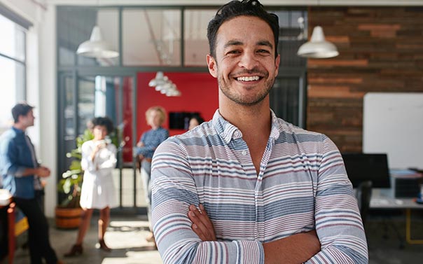 Young business individual standing in office with team behind